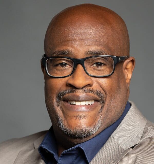 Jeff Harris smiling in front of grey background